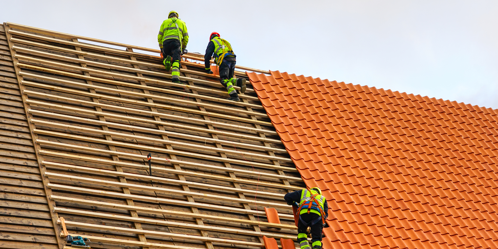 Workers installing tiles on a roof.