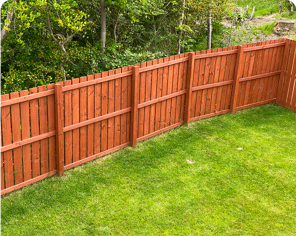 Wooden fence bordering a green grassy yard.